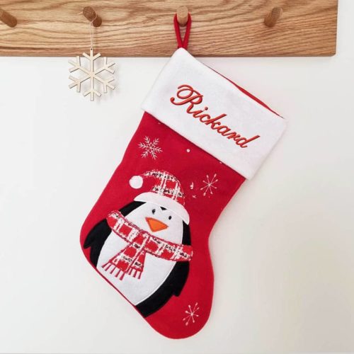 Red and white Christmas stocking with name and penguin